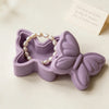 A purple silicone resin mold shaped like a butterfly with a pearl necklace inside, displayed on a light surface.