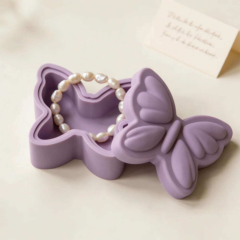 A purple silicone resin mold shaped like a butterfly with a pearl necklace inside, displayed on a light surface.