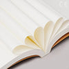 A close-up view of a Kraft paper DIY notebook with blank pages, showing the layered paper texture and soft light.