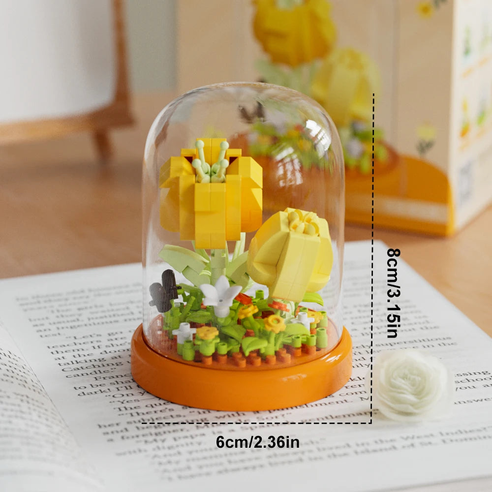 A clear glass dome showcases a DIY flower bouquet made from yellow and green building blocks on an orange base.