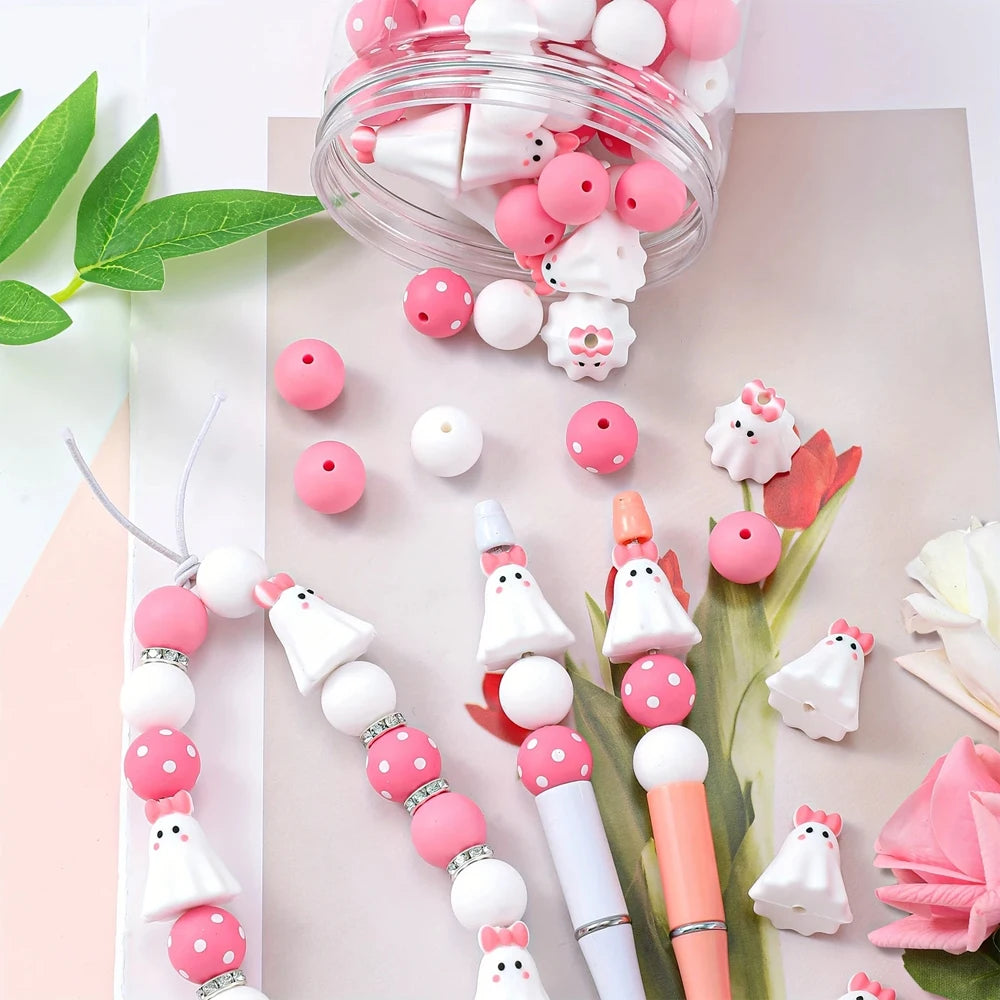 A clear jar filled with pink and white silicone beads for jewelry and crafting, alongside a string of matching beads.