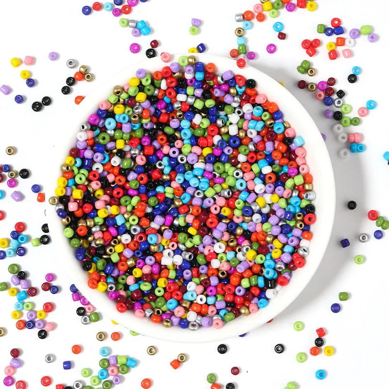 A bowl filled with 24 colors of small glass seed beads for jewelry making and DIY crafts.