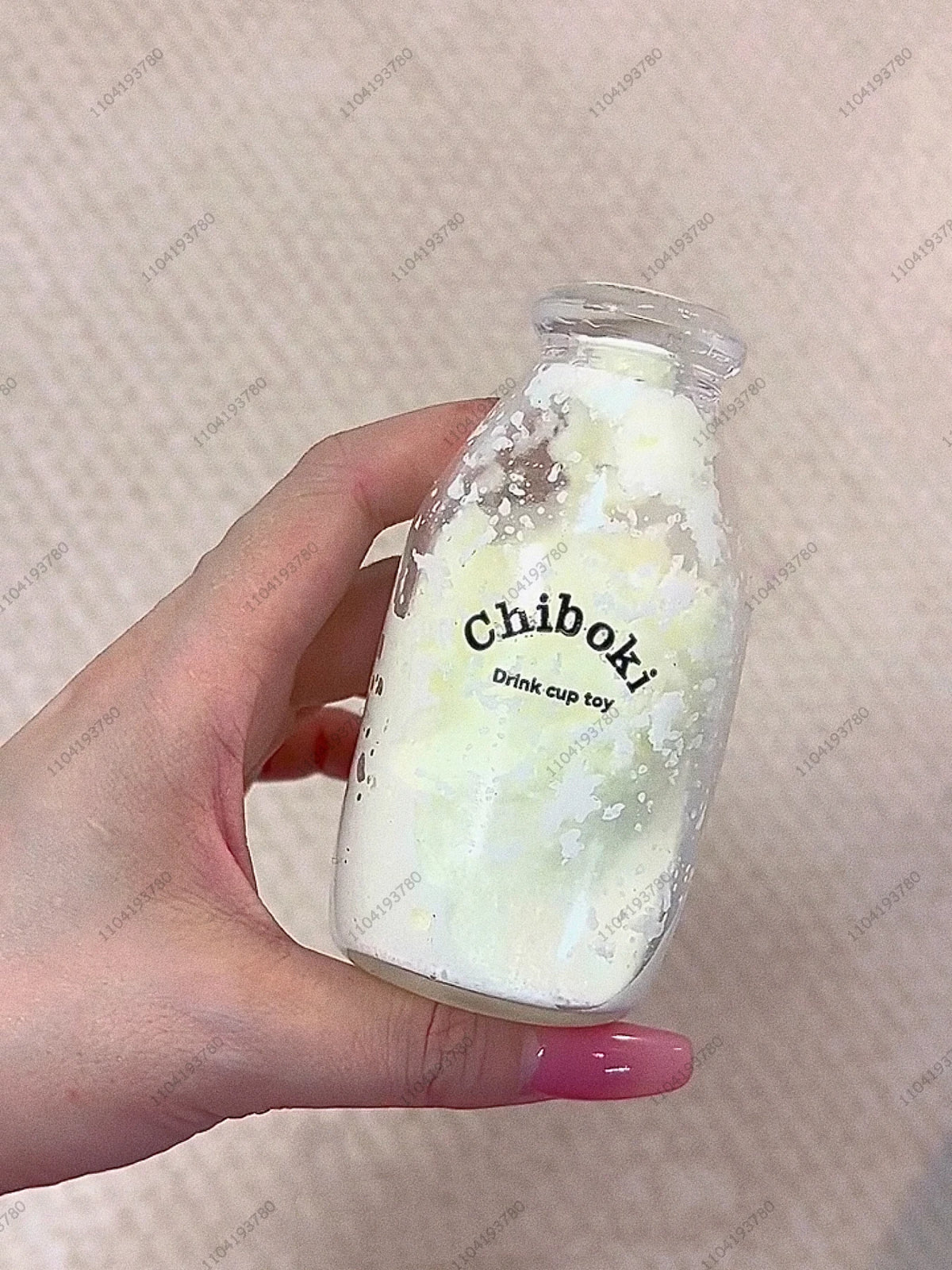 A hand holds a clear bottle filled with white and green liquid, labeled Chiboki drink cup toy.