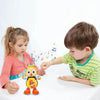 A young girl and boy interact with an electric dancing bee musical toy on a white table.