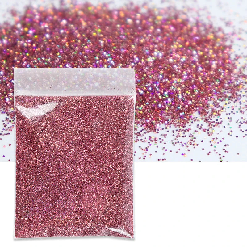 A sealed bag of holographic pink glitter powder scattered across a white background.