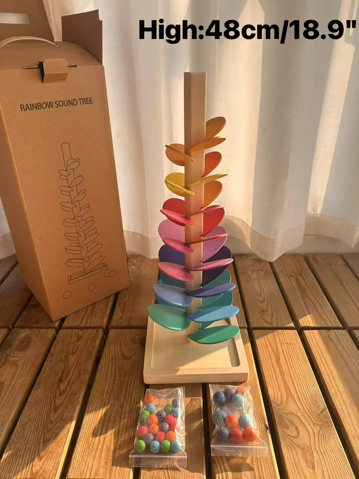 A wooden sensory music tree with a marble run featuring colorful, stacked, translucent plastic pieces.