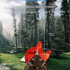 An orange electric retractable spider web launcher prop is shown outdoors in a grassy forest setting.