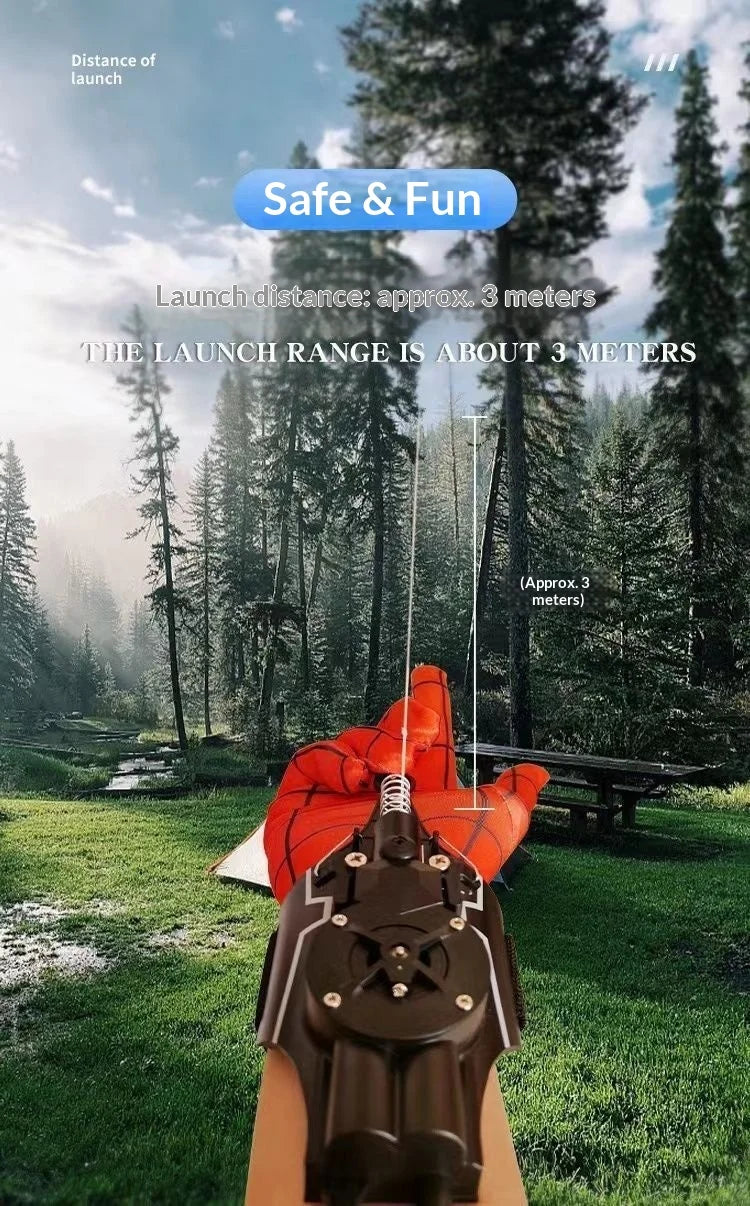 An orange electric retractable spider web launcher prop is shown outdoors in a grassy forest setting.