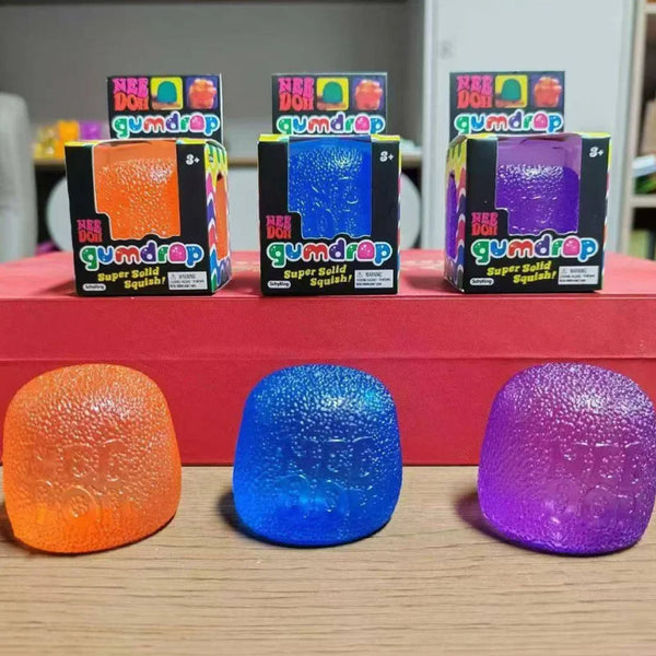 Three colorful mini gumdrop sensory fidget toys in orange, blue, and purple are displayed with their packaging.