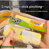 A hand squeezes a plastic stick of squishy butter, showing the material's rebound and texture.
