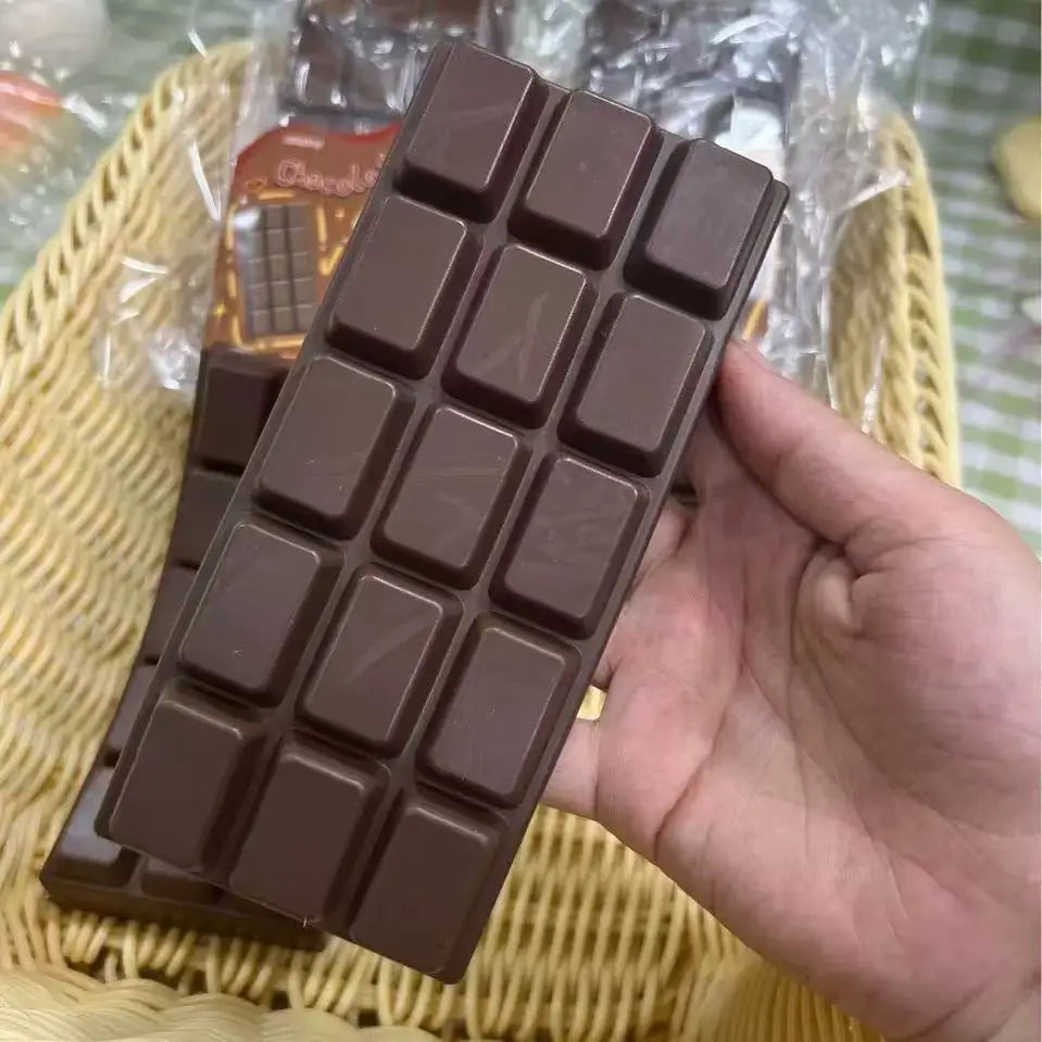 A hand holds a dark brown, squishy butter-shaped stress relief toy with a grid pattern.