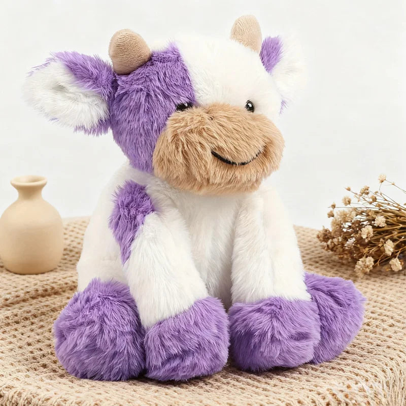 A white and purple plush toy of a cow with soft fur sitting on a beige textured surface.