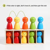 A set of colorful wooden figures in various shades of red, orange, yellow, green, and blue arranged for color matching.