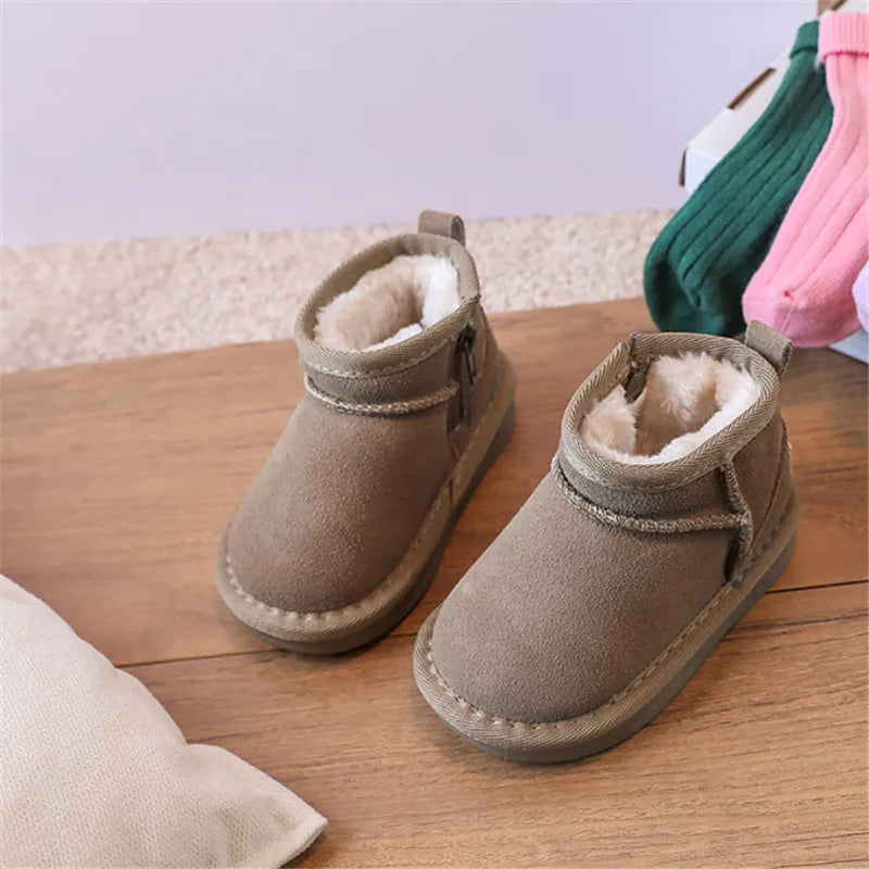 A pair of tan suede winter snow boots for toddlers resting on a wooden surface.
