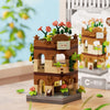 A miniature building set depicting a rustic brown wooden tower with pink flowers and green foliage.