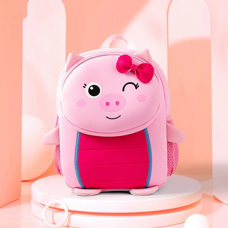 A pink pig-themed backpack with a bow, sitting on a white circular stand.