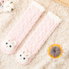Pink coral velvet baby knee-high socks with bunny feet resting on a fluffy white background