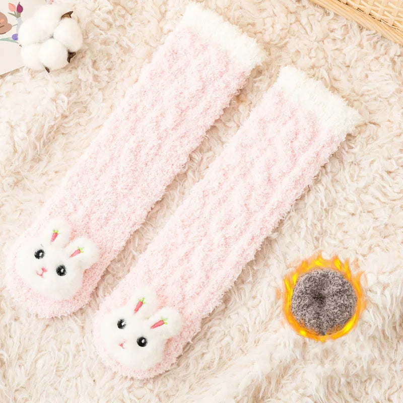 Pink coral velvet baby knee-high socks with bunny feet resting on a fluffy white background