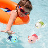 A young child wearing sunglasses is playing in water with a bright orange inflatable ring and several floating cartoon monkey