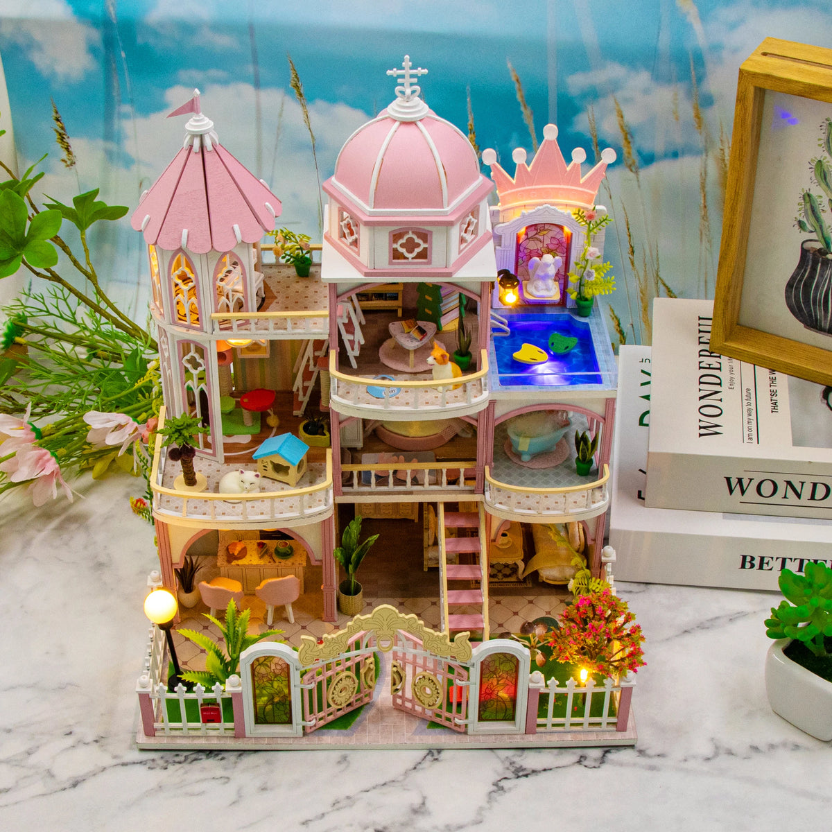A detailed wooden dollhouse kit of a Windsor castle featuring pink and white architecture with LED lighting and furniture.
