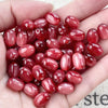 A handful of glossy, reddish-pink resin star-shaped beads for jewelry making.