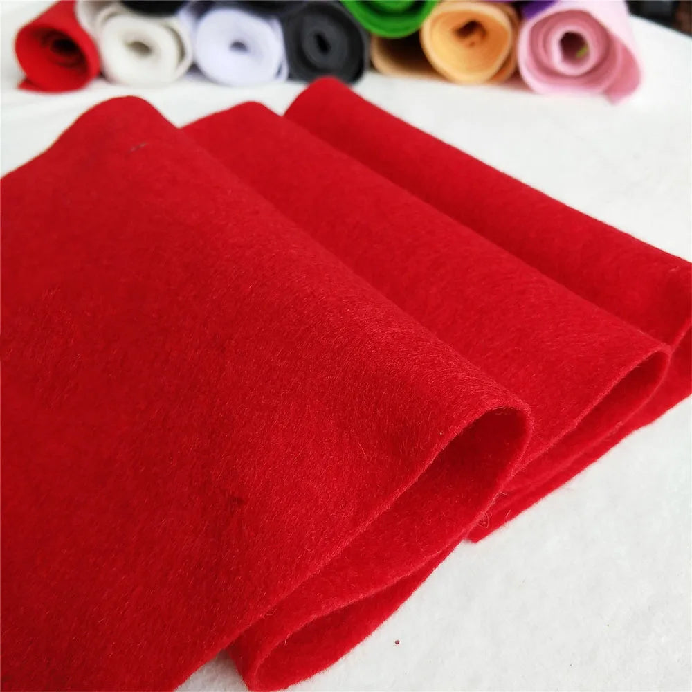A stack of bright red felt fabric sheets rolled and laid out on a white surface.