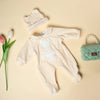 A cream-colored animal romper set for a baby, including a matching knitted hat and a green handbag.