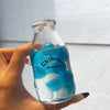 A hand holds a clear bottle filled with blue liquid and numerous blue bubbles, labeled Chiboki.