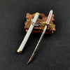 A samurai sword keychain featuring a silver blade, white grip, and gold accents, resting on a brown wooden background.