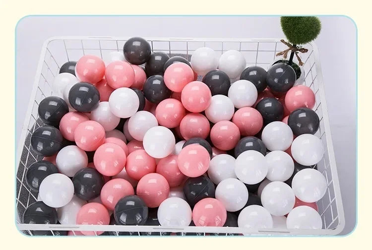 A white plastic basket filled with 50 colorful play balls in shades of pink, black, and white.