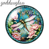 A round glass cabochon featuring a detailed floral and insect design in shades of green, purple, and pink.