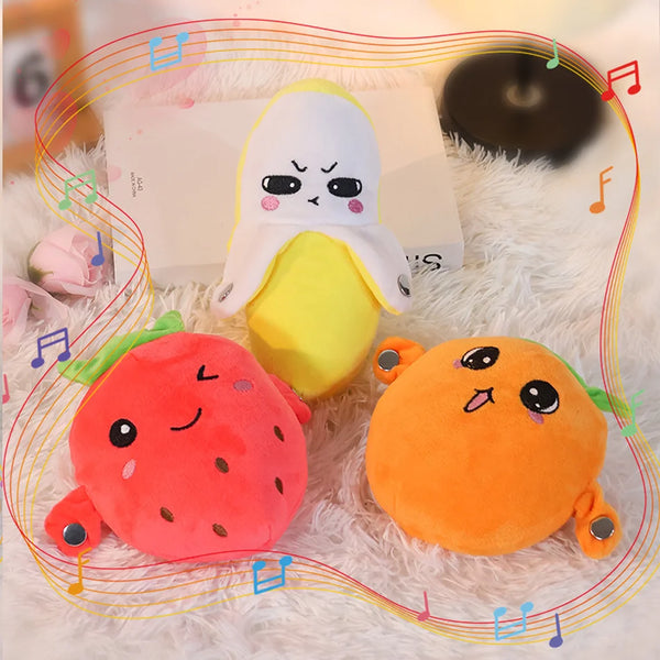 A yellow and white plush toy resembling a fruit, next to an orange strawberry plush toy on a white fuzzy surface.