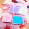 A collection of diamond painting clay in various colors, including pink, purple, and blue, displayed on a textured surface.