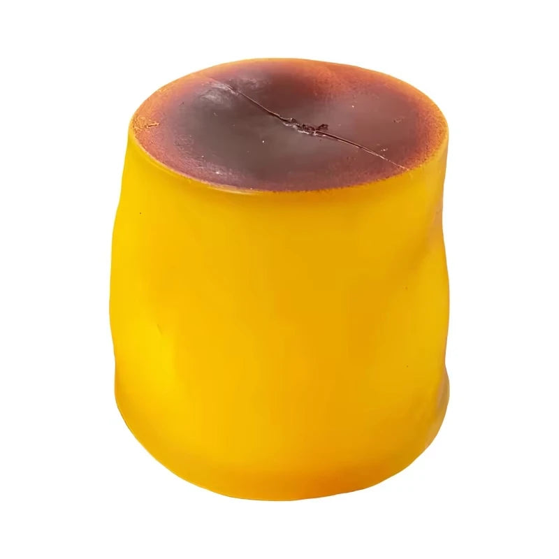 A round, yellow caramel pudding stress ball with a dark brown top and visible cracks.