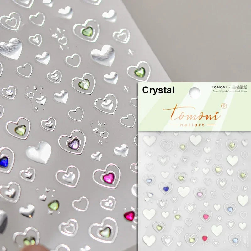 Silver heart-shaped nail art stickers with various colored accents on a white background