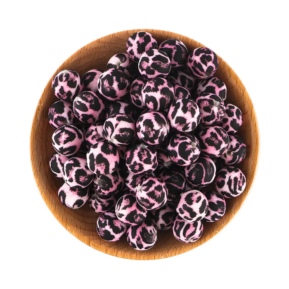 A pile of pink and black leopard print silicone beads in a wooden bowl.