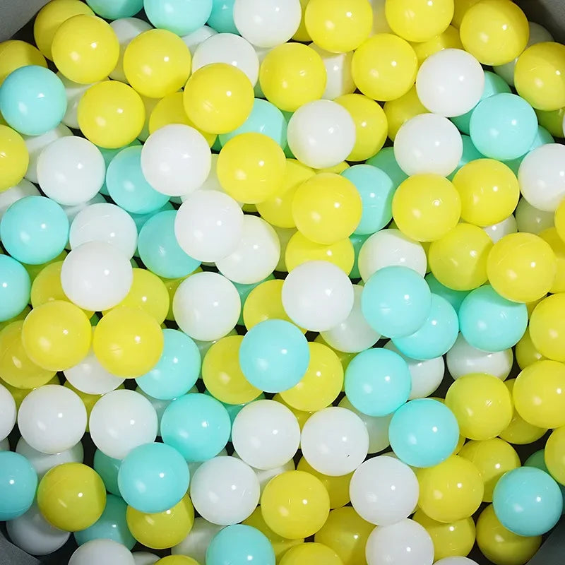 A bulk set of colorful plastic ocean ball pit toys in various shades of yellow, white, and light blue.
