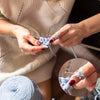 Hands are shown adjusting an adjustable cat-ear crochet ring with tension control on a finger.