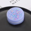 A purple biscuit squishy stress relief toy with colorful sprinkles resting on a dark gray plate.