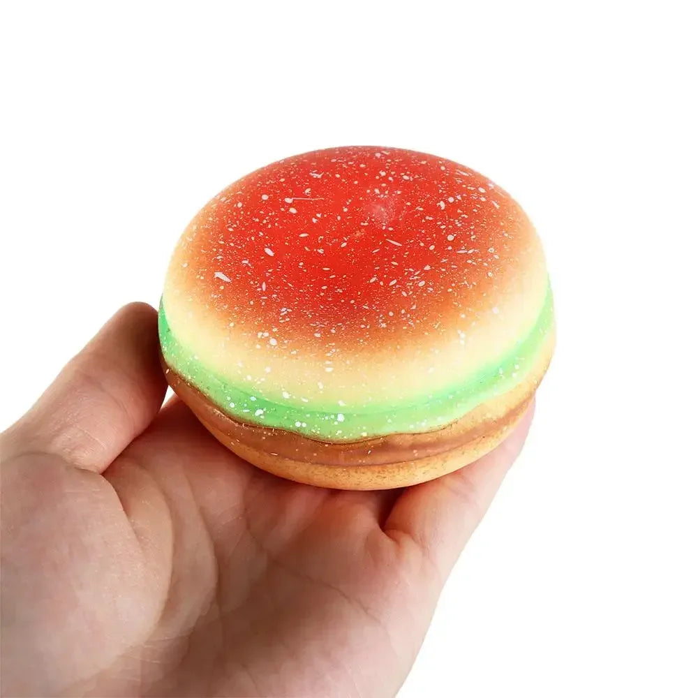 A round, squishy stress ball shaped like a burger with red and green icing and sprinkles.
