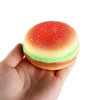 A round, squishy stress ball shaped like a burger with red and green icing and sprinkles.