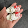 A pair of white fashion slippers for a doll, decorated with pink and red polka dots.