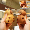 Hands hold two orange capybara squeeze toys that are pinching to blow bubbles.