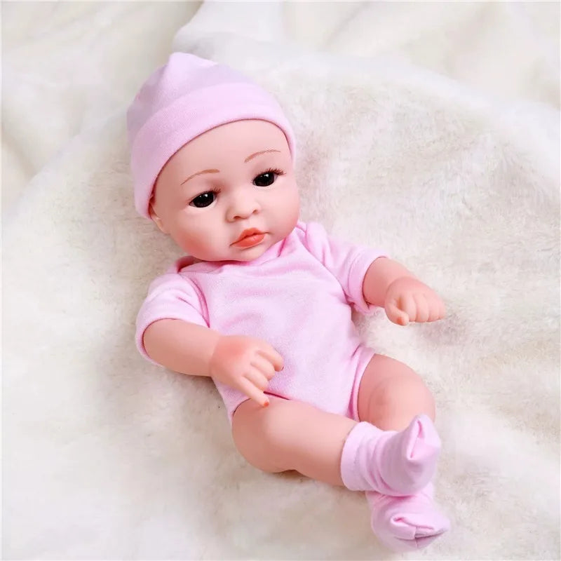 A pink reborn doll wearing a matching pink cozy winter romper outfit, lying on a white fluffy surface.