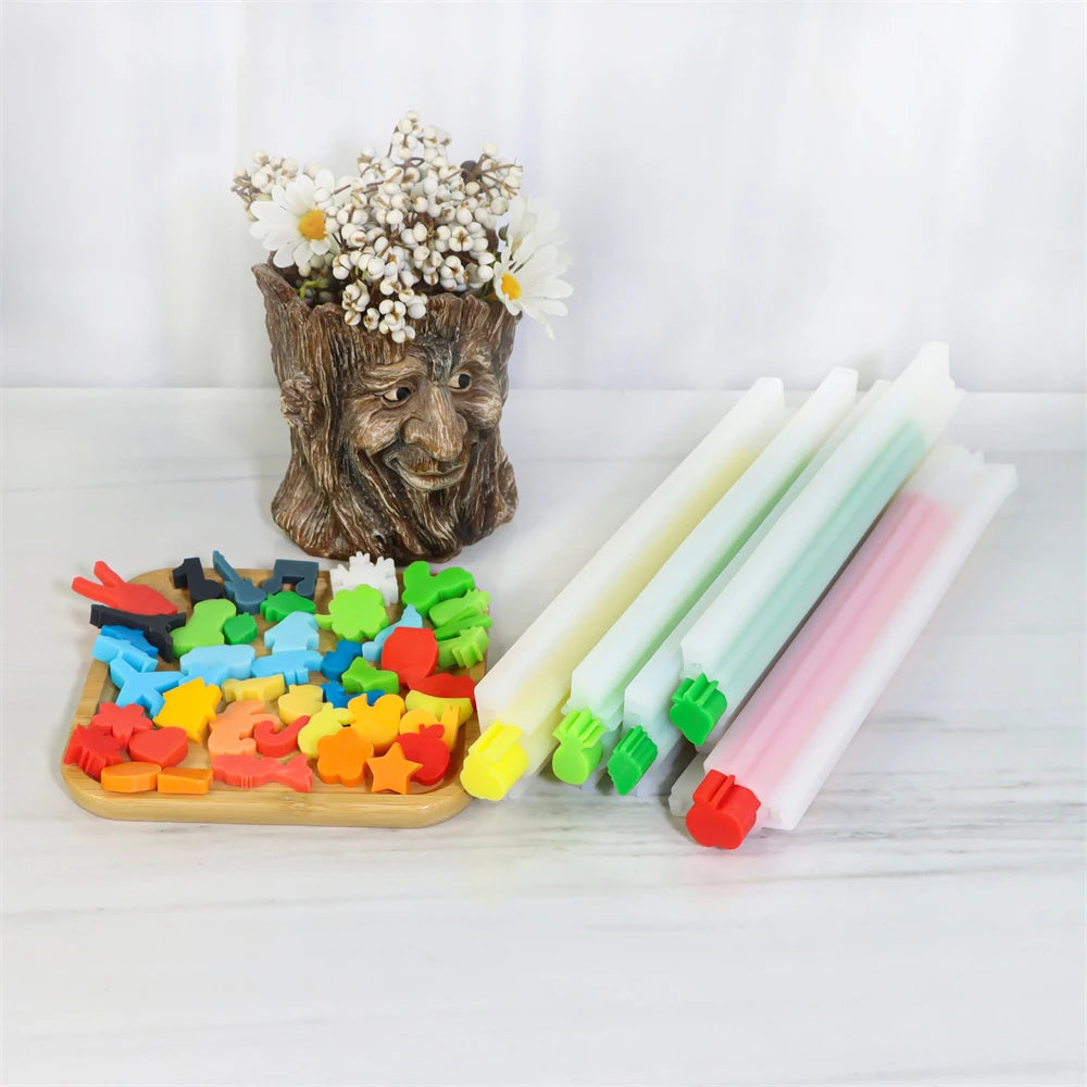 A set of 50 silicone soap and candle molds featuring assorted shapes in various colors, displayed next to a potted plant.
