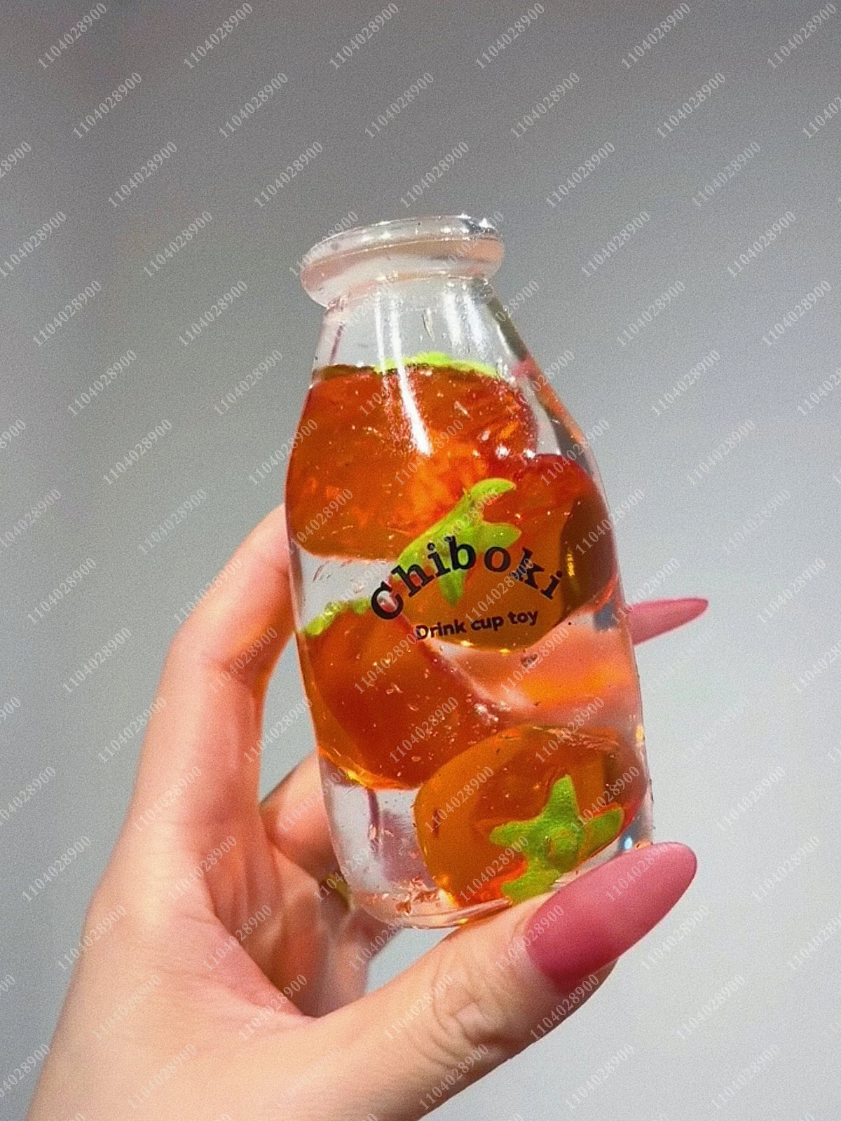 A hand holds a clear glass bottle filled with orange-colored squishy stress balls labeled Chiboki.