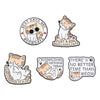 A set of four enamel pins featuring cute cat designs and motivational phrases.