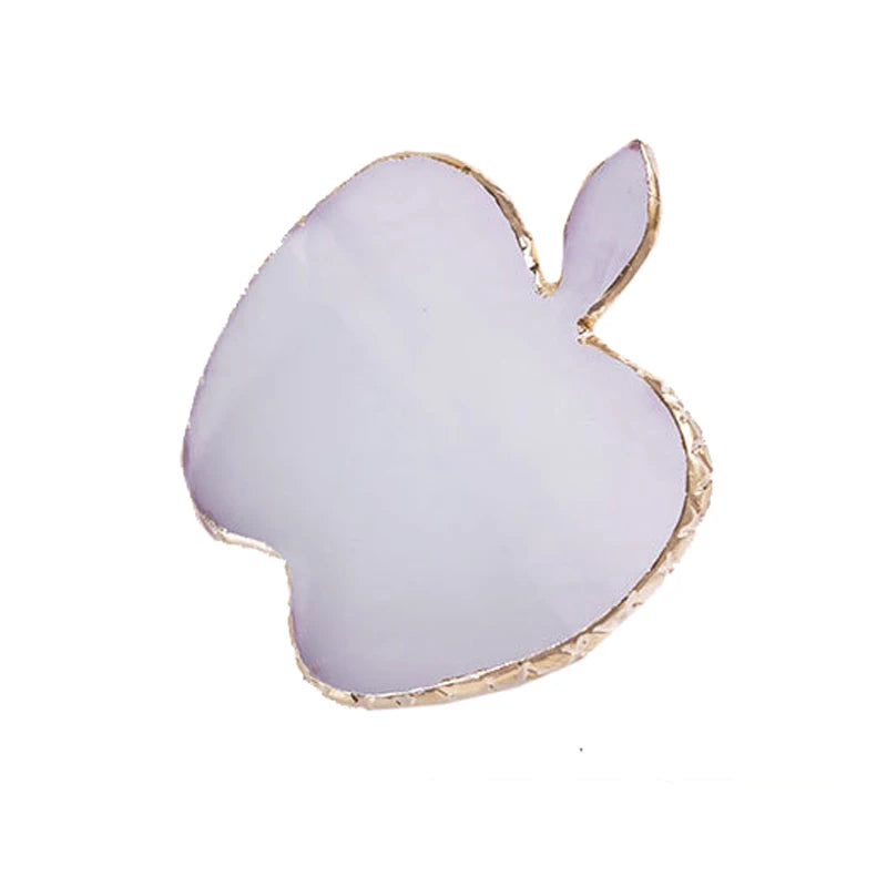 A pale purple resin nail art palette with a gold trim shaped like an apple.