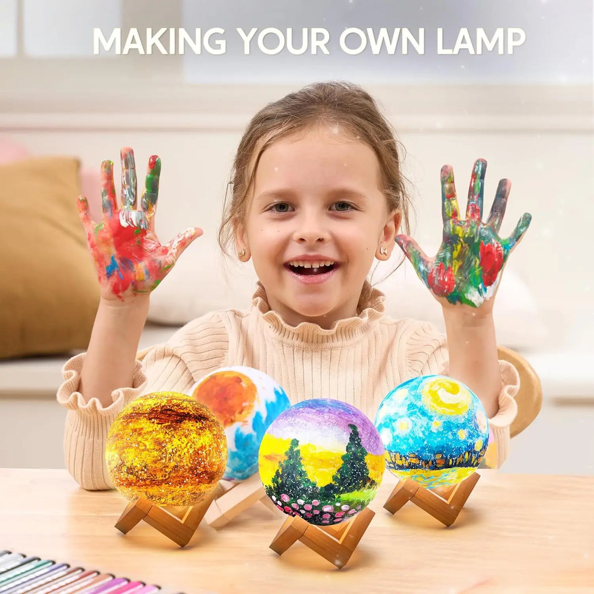A smiling girl holds five colorful, spherical craft items on a wooden table for a DIY moon night light kit.