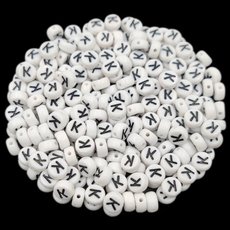 A pile of small white acrylic alphabet letter beads for jewelry making